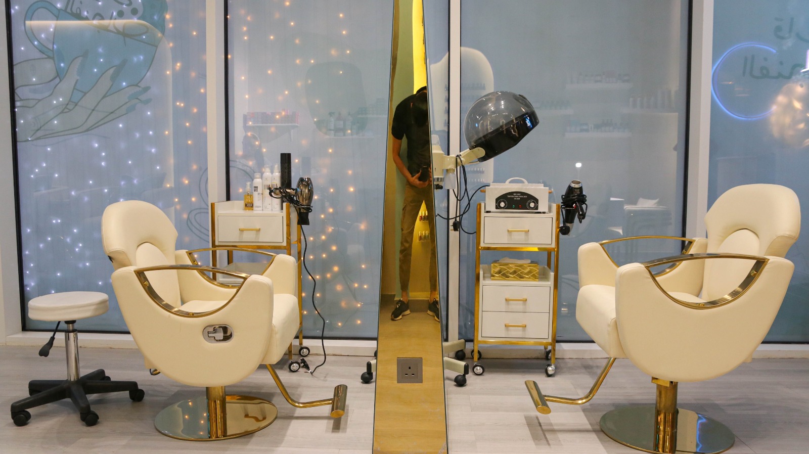 Twin cream and gold styling stations with tall mirror at Qareat Al Fenjan